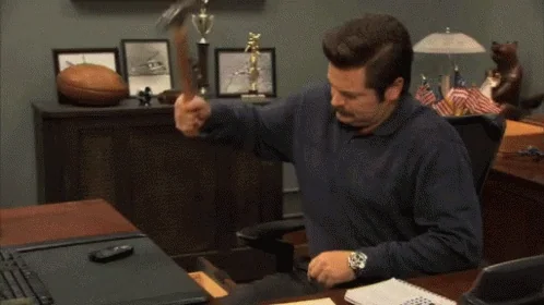 Hombre en una oficina revisando documentos, con un escritorio y trofeos al fondo